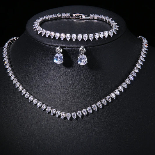 Elegant jewelry set with a teardrop crystal necklace, matching bracelet, and earrings displayed on a black background, showcasing sparkling, clear stones.
