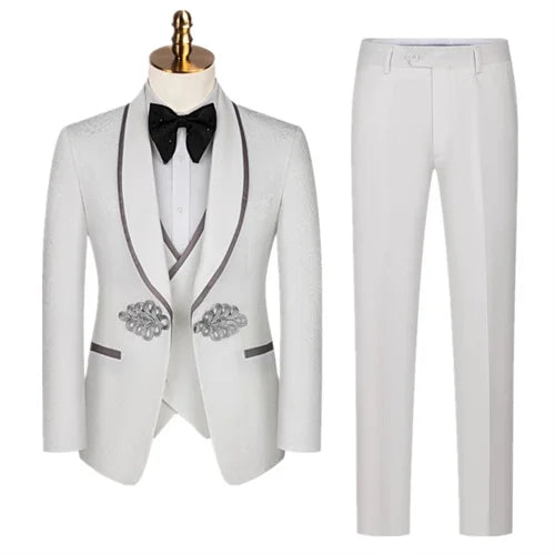 White tuxedo with black lapel trim, featuring a bow tie, embellished pockets, and matching pants. The suit is displayed on a mannequin and appears formal and elegant.