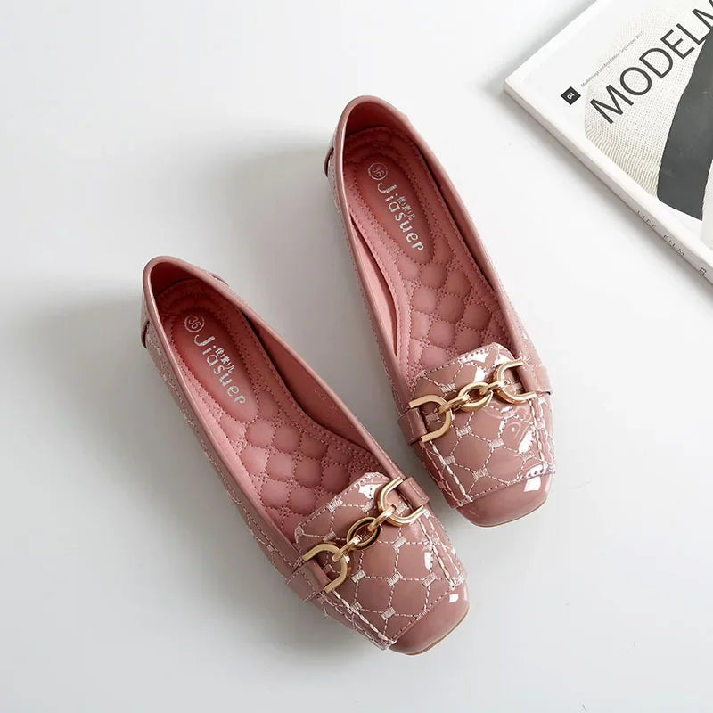 Pink quilted flats with gold chain detail, placed on a white surface near an open magazine.
