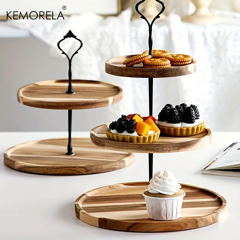 Three-tier wooden dessert stand holds crackers, fruit tarts, and a cupcake. Another empty stand is in the background. Bright, elegant setting with soft lighting.