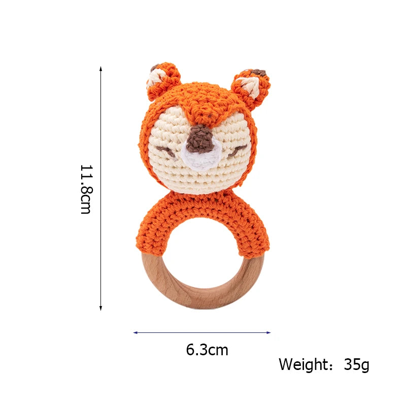Orange crochet fox teether with wooden ring handle. Dimensions: 11.8cm tall, 6.3cm wide, and weights 35g. Fox features include eyes, nose, and ears.