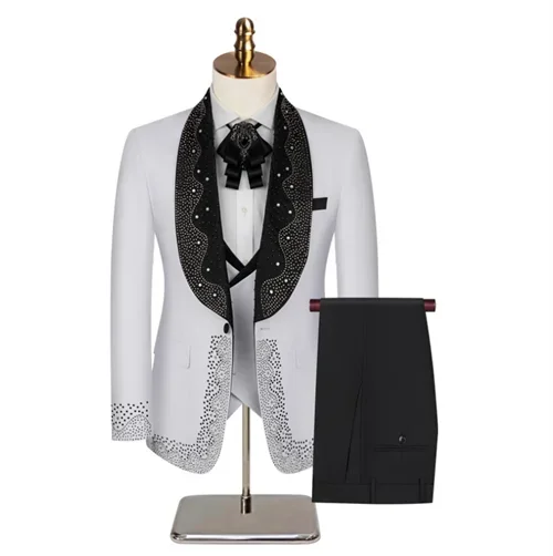 A white mariachi-style suit on a mannequin features a black, embellished, scalloped collar with matching cuffs and trim, paired with a black necktie and trousers.