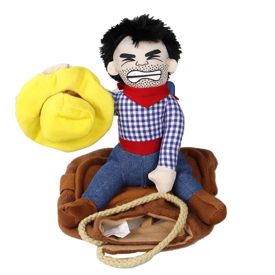 A plush cowboy doll with a checkered shirt, red bandana, and blue jeans holds a yellow hat. It sits atop a textured brown mat with rope edges.