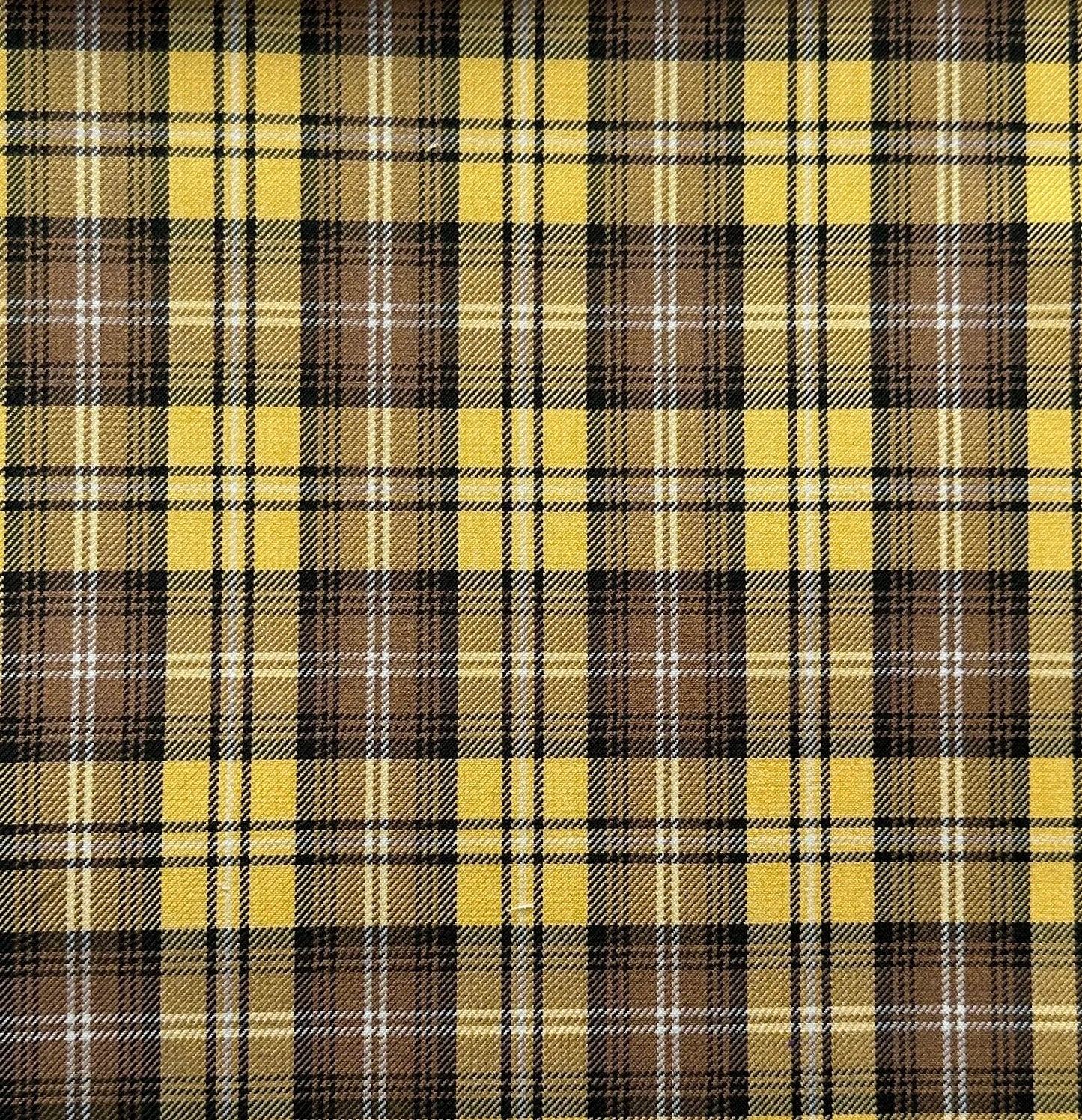 Plaid pattern with yellow, brown, and black checks, intersected by white lines, creating a classic tartan design.