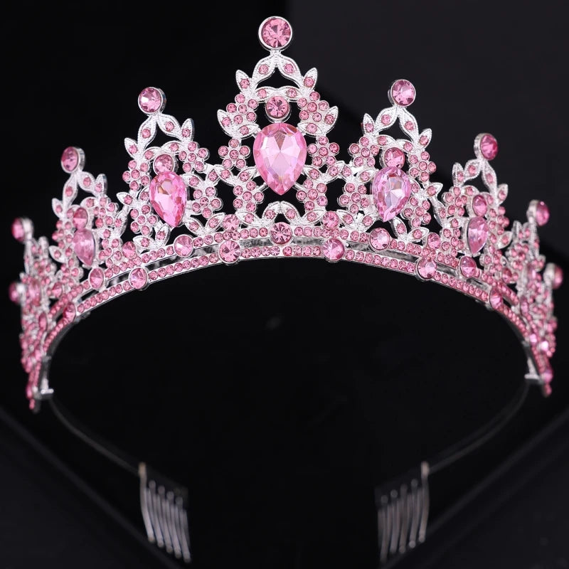 Silver tiara adorned with intricate pink gemstones, featuring large pear-shaped stones and delicate floral detailing against a black background.