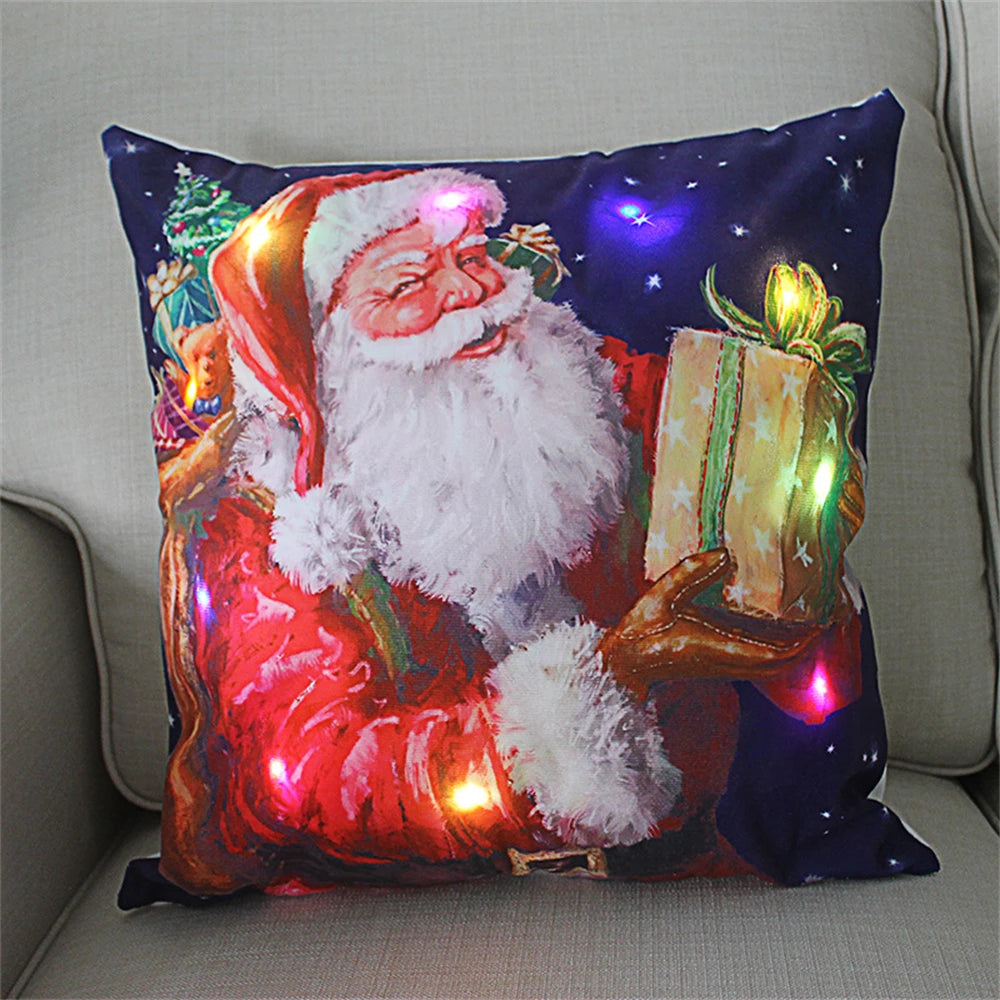 Festive pillow featuring Santa Claus with a gift. The design includes colorful LED lights highlighting Santa's hat, beard, and the present. Starry background completes the holiday theme.