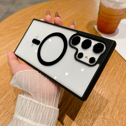 A hand holds a smartphone with a sleek black and white case featuring a unique circular design. The phone rests on a wooden table next to a cup of iced beverage.