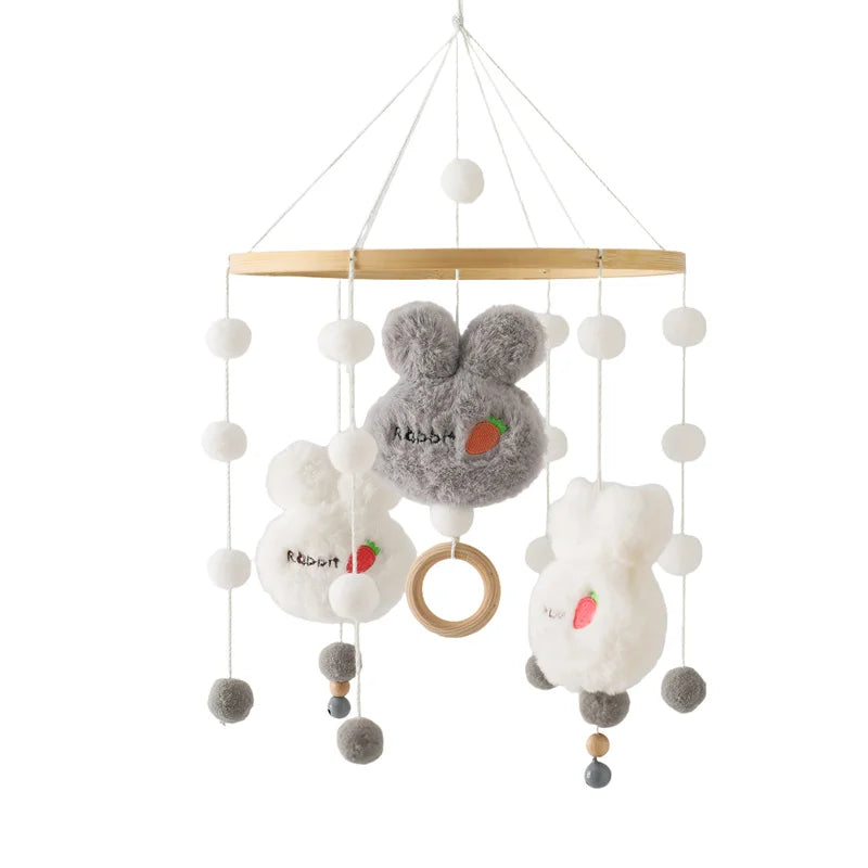 Soft baby mobile with plush rabbit shapes, featuring white and gray bunnies, pom-poms, and a wooden ring. Each bunny is embroidered with a carrot and the word "Rabbit."