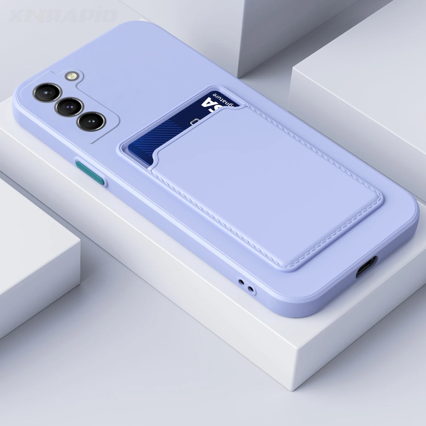 A light purple phone case with three camera lenses and a card slot holding a blue card. The case has a soft finish and is placed on a white surface with geometric shapes.
