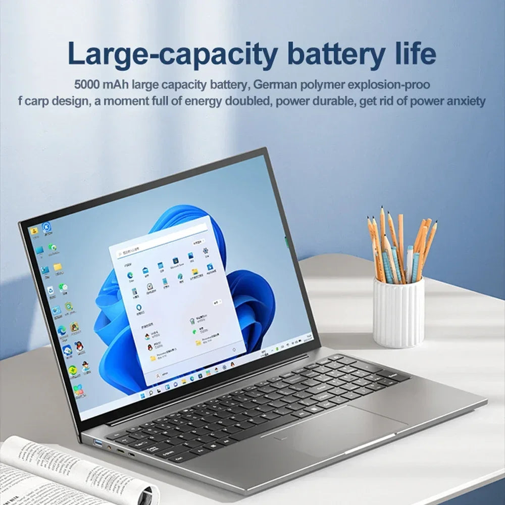 A sleek laptop with a large display sits on a desk next to a cup of pencils and a rolled-up magazine. The screen shows a Windows interface with a blue abstract background. Text above highlights the large-capacity battery life.