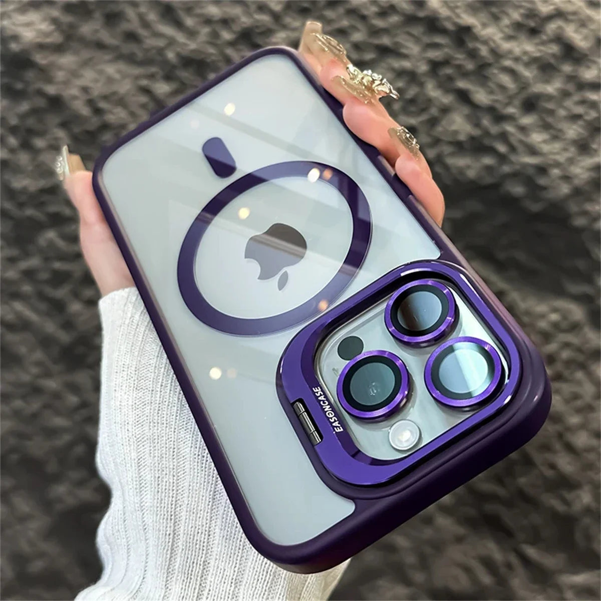 A person holding a phone with a purple and clear case showcasing the Apple logo. The case features purple camera lens accents and the brand name "Elago" is visible.