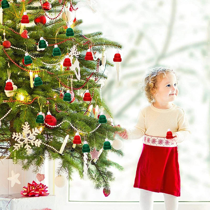 A child in a red dress admires a decorated Christmas tree adorned with ornaments, lights, and small knit hats. Snowflake and icicle ornaments add a festive touch.