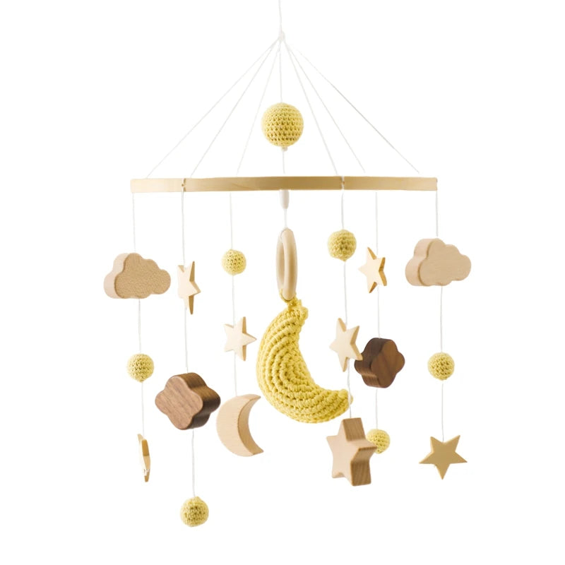 A charming baby mobile with wooden clouds, stars, and a crocheted yellow moon, all hanging from strings attached to a circular wooden frame.