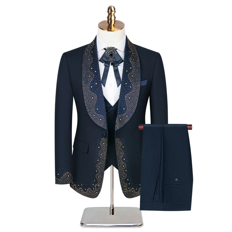 Elegant navy suit with intricate gold embroidery on lapels and cuffs, paired with a matching vest, tie, and trousers. Displayed on a mannequin with a gold stand.