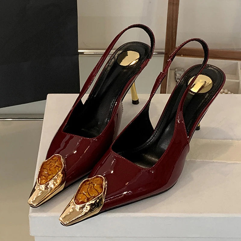 Elegant maroon patent leather slingback heels with gold and amber-toned decorative tips, featuring gold accents on the insole and slender heels, displayed on a white surface.