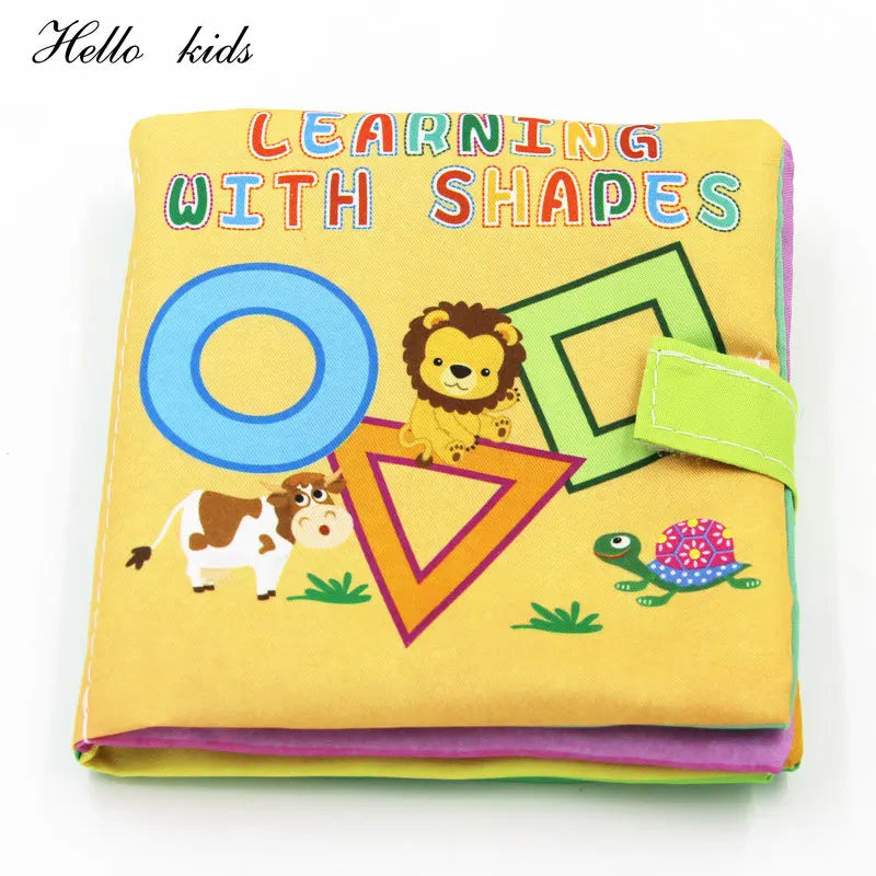 Brightly colored children's cloth book titled "Learning with Shapes," featuring a lion, cow, and turtle with various shapes on a yellow background.
