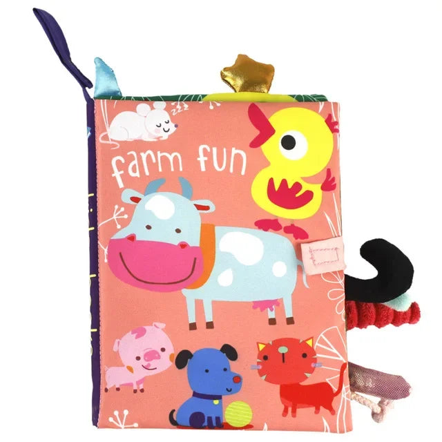 Colorful children's cloth book titled "Farm Fun" featuring cartoon animals: a cow, duck, pig, dog, cat, and mouse on a pink background. Tabs and tags add tactile elements.