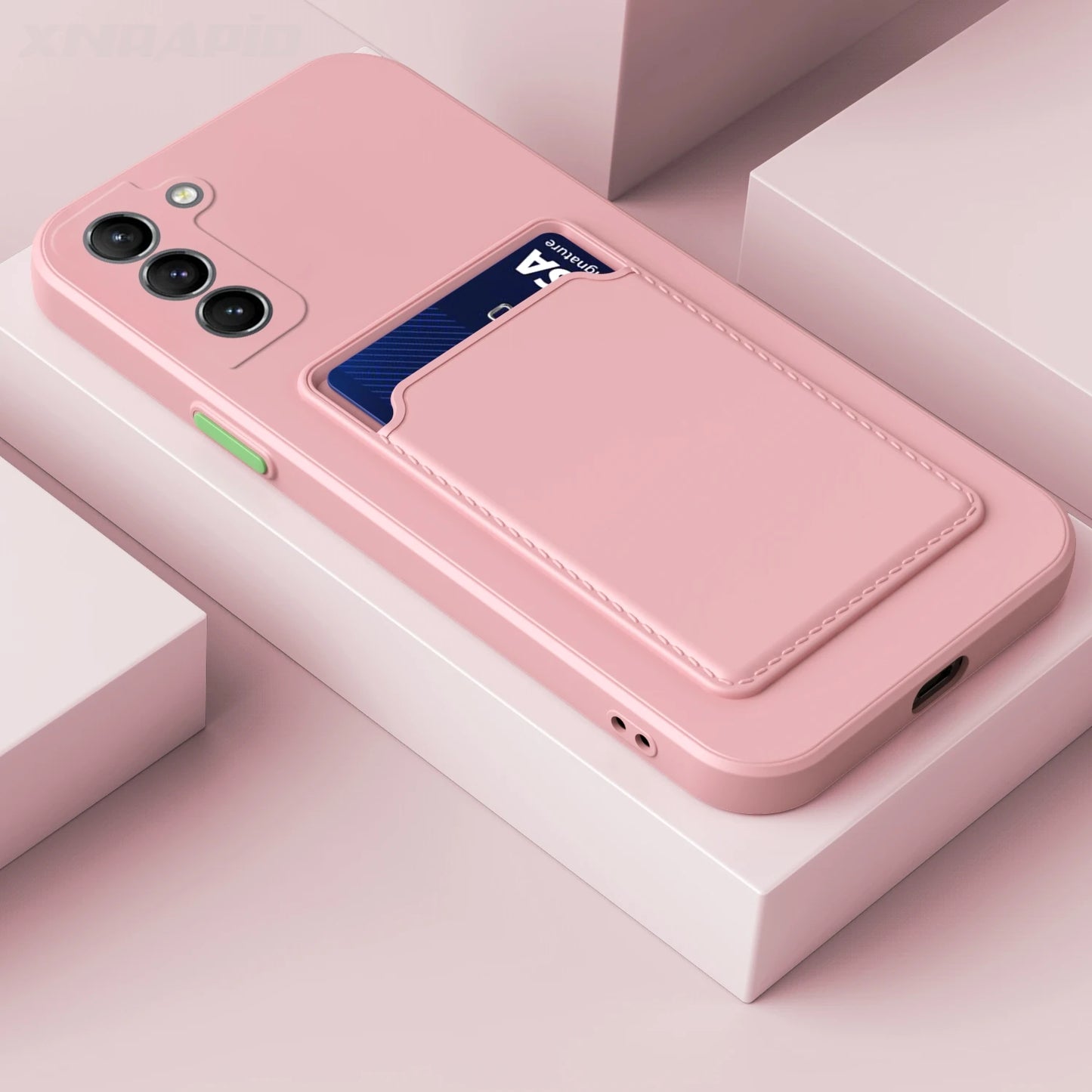 Pink smartphone case with three camera lenses and a rear card holder slot containing a blue card. The case rests on a white geometric surface.