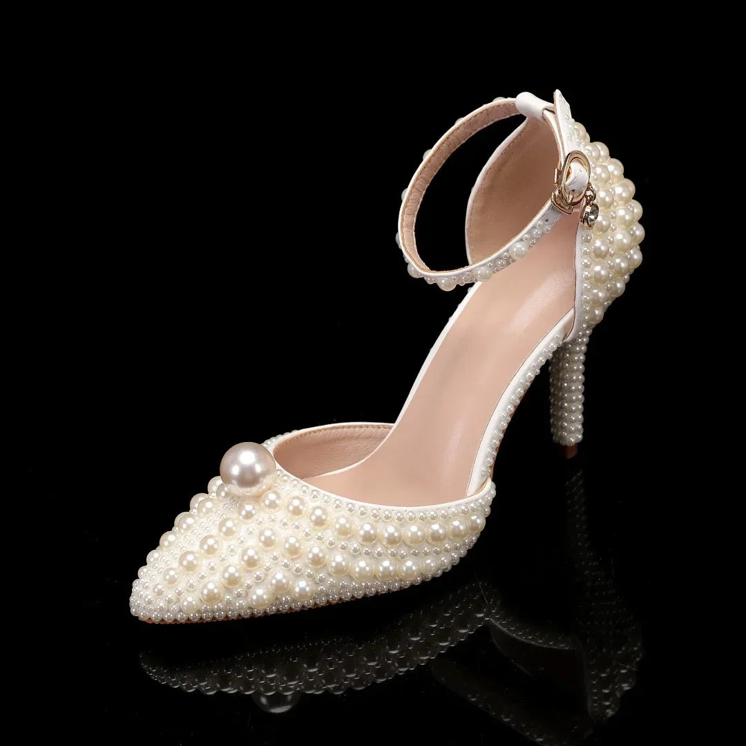 Elegant high-heeled shoe adorned with pearls, featuring a pointed toe, ankle strap, and stiletto heel. Each surface is covered with small pearls, except for the inner sole.
