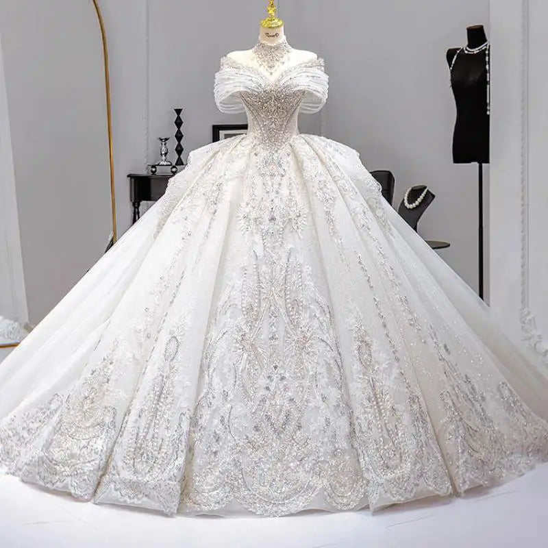 Elegant white ball gown with intricate lace details on a mannequin in a chic boutique. The dress features an off-the-shoulder neckline and a voluminous skirt, surrounded by accessories.