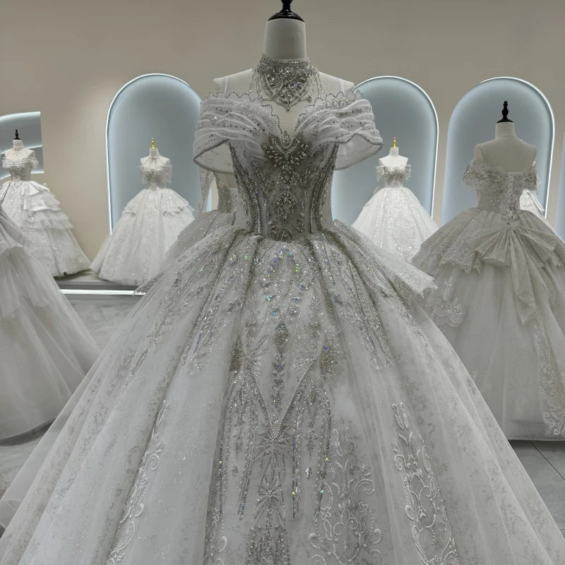 A stunning white ball gown with intricate beadwork and lace details, displayed on a mannequin in a bridal boutique. Mirrors showcase other elegant gowns in the background.