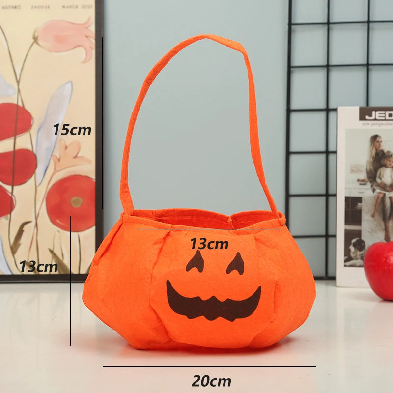 Orange pumpkin-shaped bag with a black Jack-o'-lantern face. It has a handle and measures 20cm wide, 13cm depth, and 15cm tall, displayed on a table with decorative items.