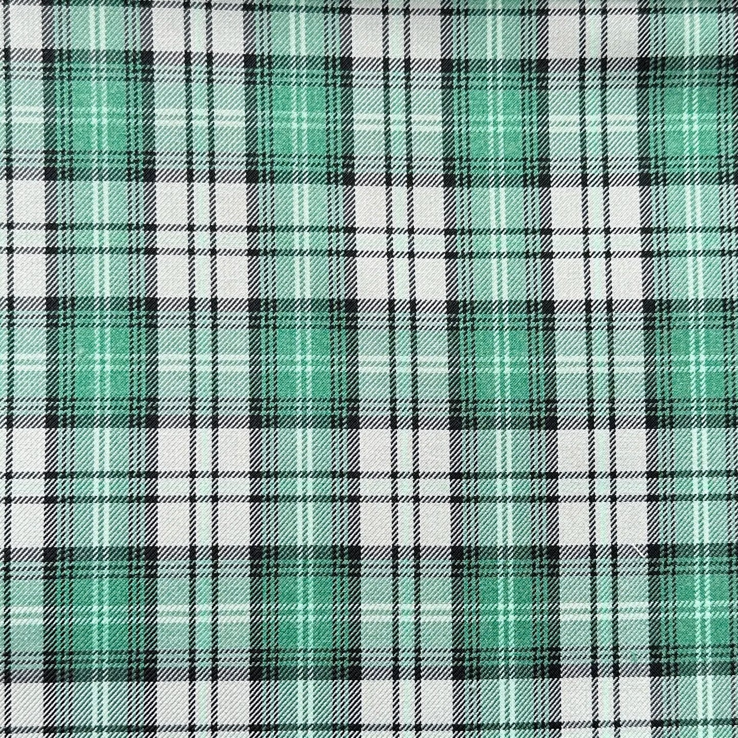 Plaid pattern with a mix of green, black, and white lines intersecting to form squares. The green squares are prominent, creating a vibrant and symmetrical design.