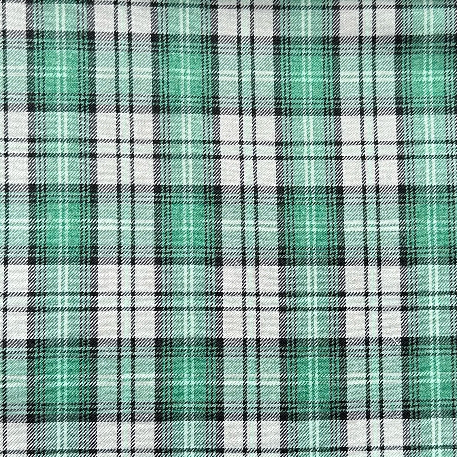 Plaid pattern with a mix of green, black, and white lines intersecting to form squares. The green squares are prominent, creating a vibrant and symmetrical design.