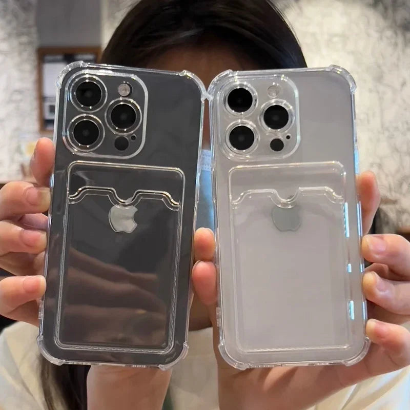 Two hands hold up two clear phone cases with attached card holders, showcasing Apple logos. The cases have triple camera cutouts and reflect light, set against a blurred indoor background.