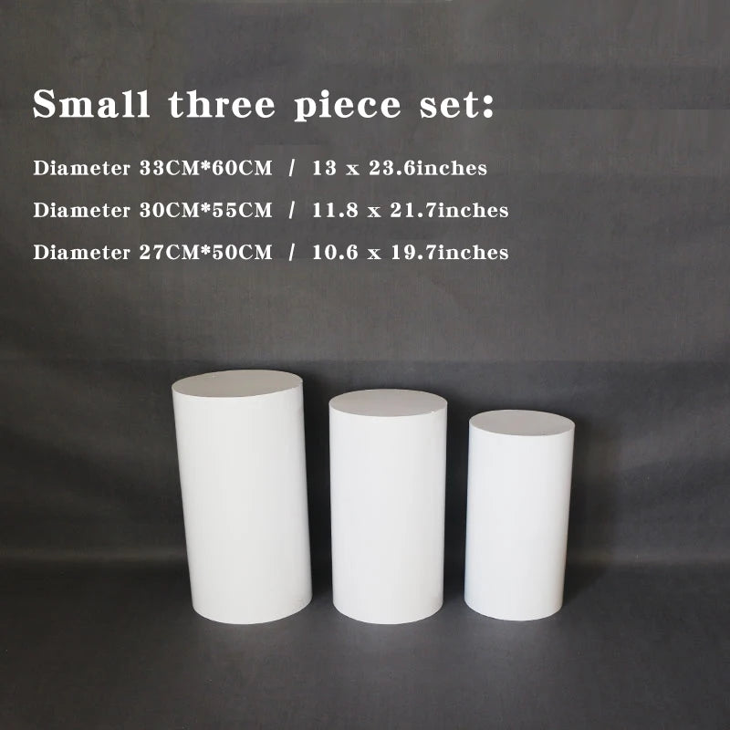 Three white cylindrical stands of varying heights and diameters are displayed against a dark background. Dimensions are listed above: 33x60cm, 30x55cm, 27x50cm.