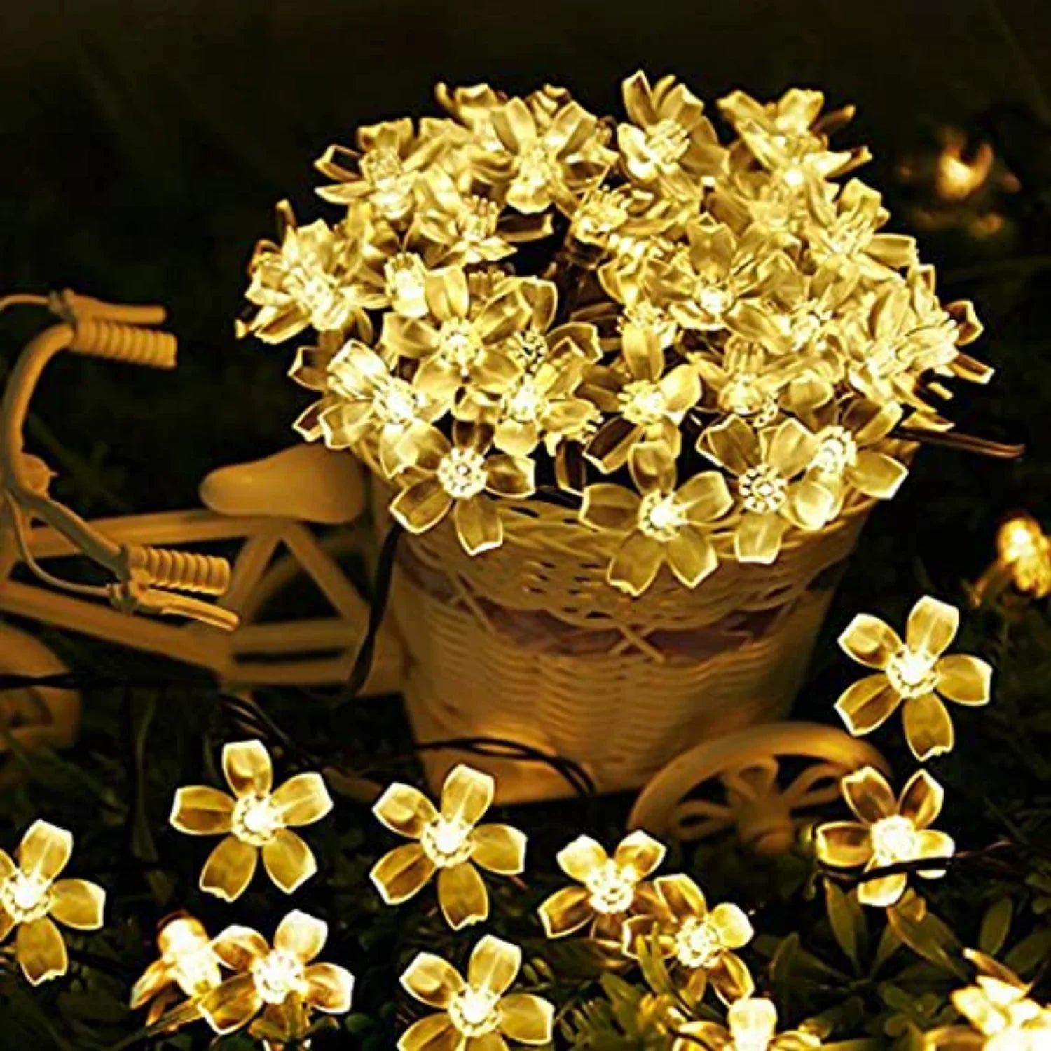 Warm yellow flower-shaped fairy lights in a woven basket on a tricycle, creating a cozy, illuminated display against a dark background.