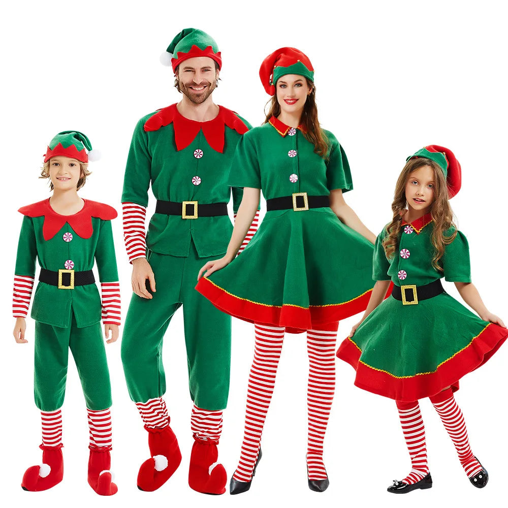 A family of four dressed in festive green and red elf costumes, with striped stockings and Santa hats, smiling against a plain white background.