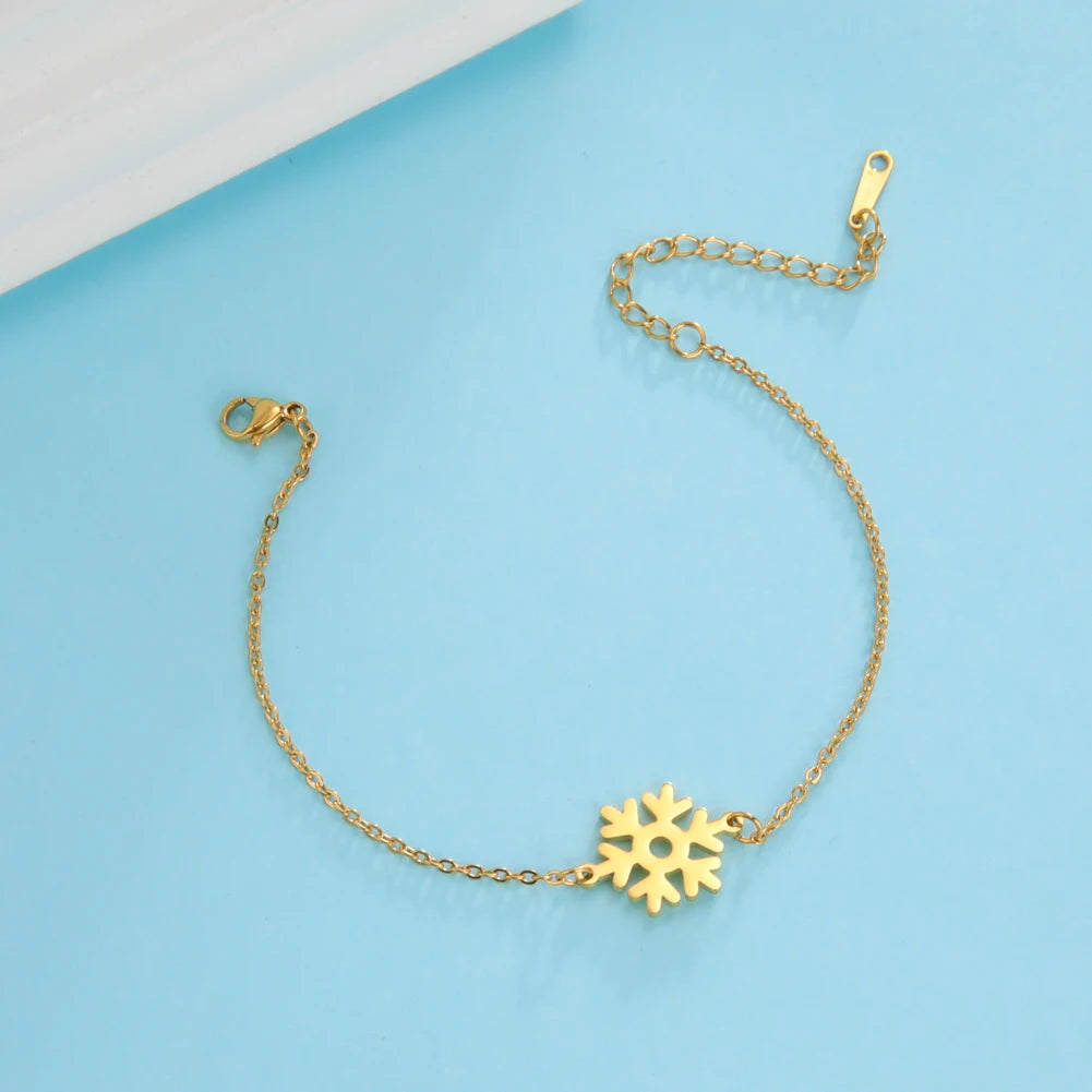 Gold bracelet with a delicate snowflake charm on a light blue background. Features an adjustable chain and clasp for secure fastening, combining elegance with a winter theme.