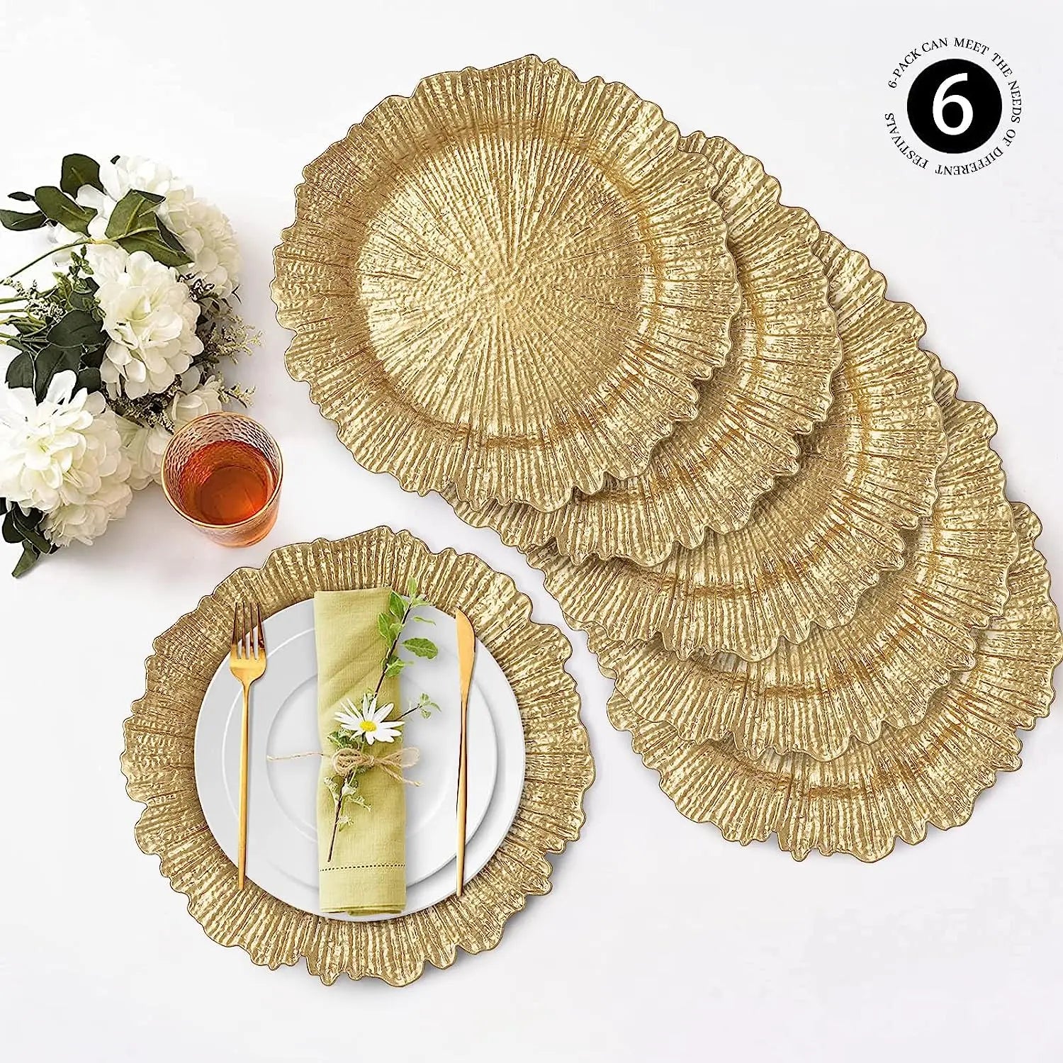 Gold textured charger plates arranged on a white table with white flowers, a gold fork and knife, and a glass of amber liquid. A green napkin with a daisy embellishes a place setting.