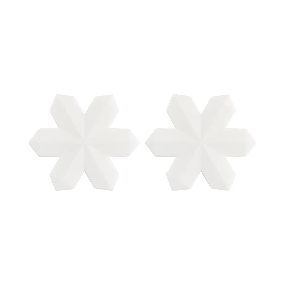 Two white, geometric snowflake-shaped objects with six symmetrical, pointed arms each, placed side by side on a plain white background.