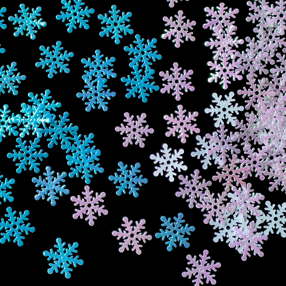 Colorful glittery snowflake cutouts in shades of blue and pink are scattered against a black background, creating a vibrant and festive pattern.