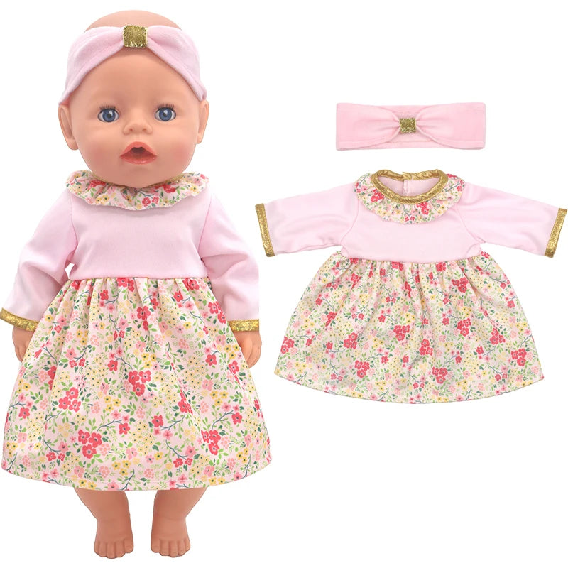 Baby doll wearing a pink dress with a floral skirt, gold-trimmed sleeves, and a matching headband. An identical dress and headband are displayed next to the doll.