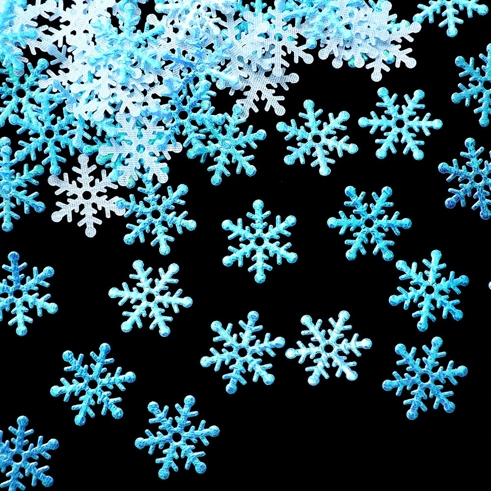 Blue and white glittery snowflake confetti scattered on a black background, highlighting their intricate designs and shimmering texture.