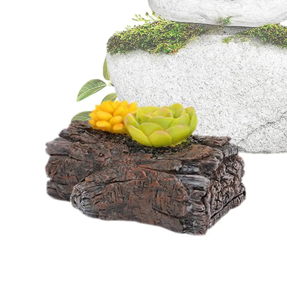 Two miniature succulent plants, one yellow and one green, sit on a textured dark brown log in front of a light-colored stone, adorned with green moss and leaves.