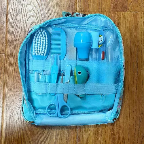 Small blue grooming kit on a wooden floor, containing a toothbrush, comb, scissors, nail clippers, a bottle, and a tool with a playful fish design, all secured neatly inside.