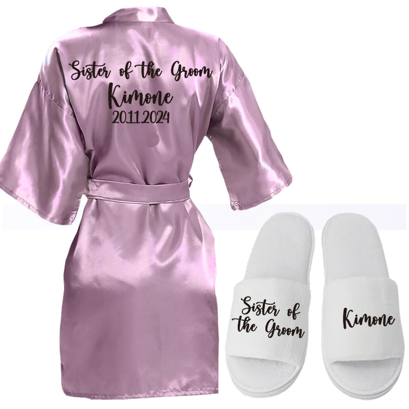 Pink satin robe with "Sister of the Groom, Kimone, 20.11.2024" on the back, paired with white slippers featuring similar text.