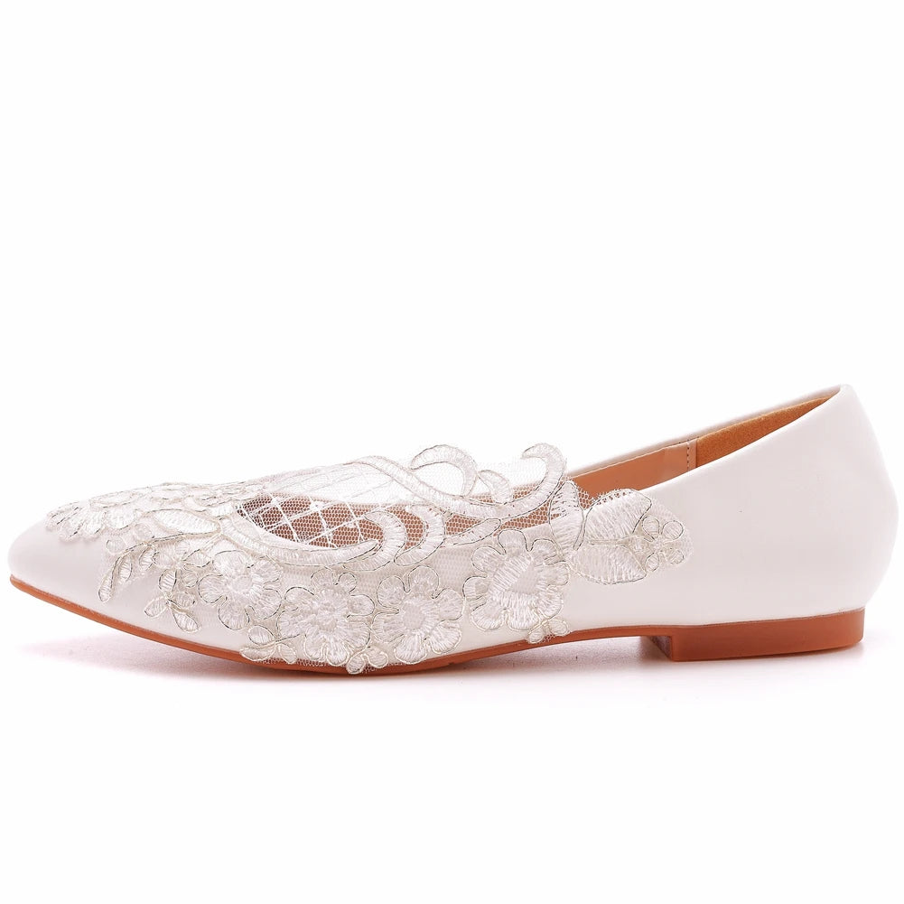 Elegant white flat shoe with intricate floral lace embroidery and a brown sole, side view.