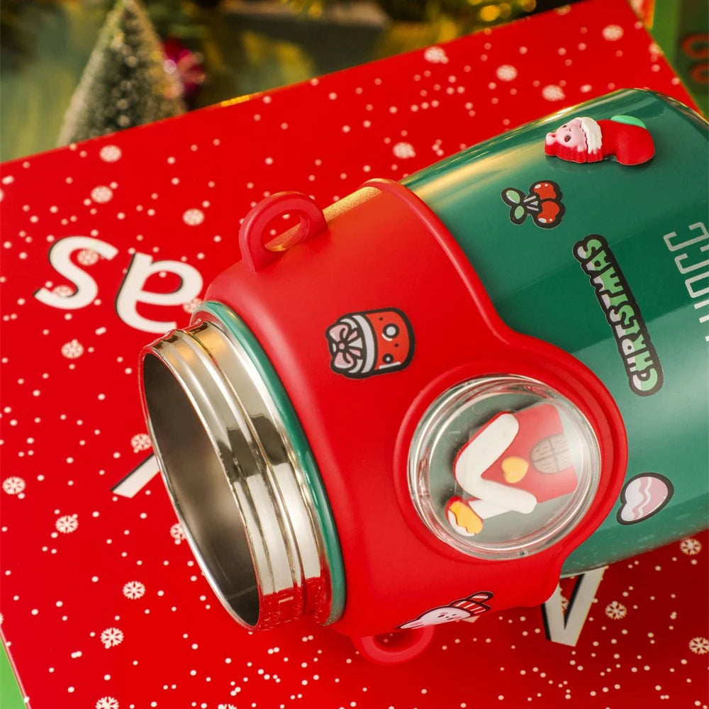 Festive tumbler with red and green Christmas-themed design, featuring Santa, cherries, and a gift on a red snowflake-patterned background.