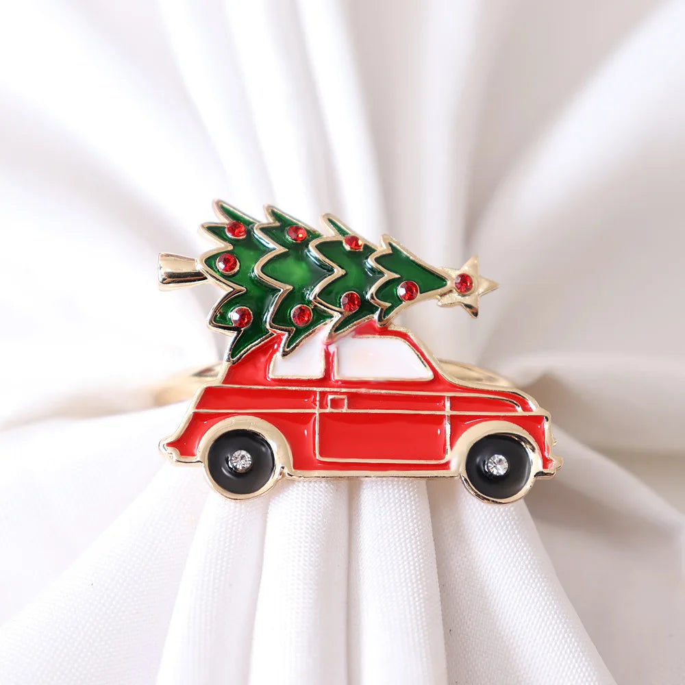 Festive holiday pin featuring a red car with a decorated green Christmas tree on top, embellished with red gems, against a background of white cloth.