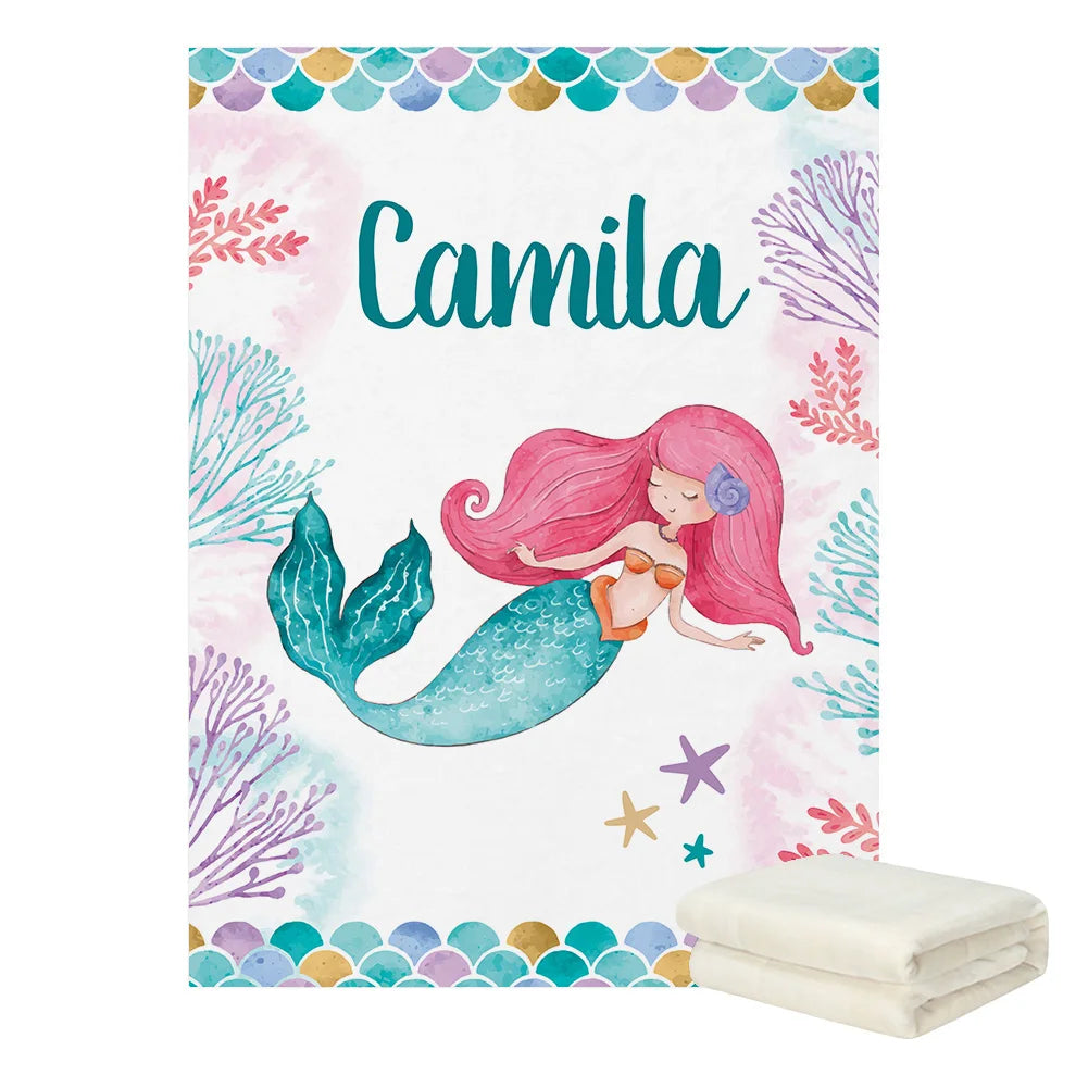 Whimsical mermaid illustration on a blanket with "Camila" text, surrounded by colorful coral and starfish designs. A folded white blanket is displayed in front.