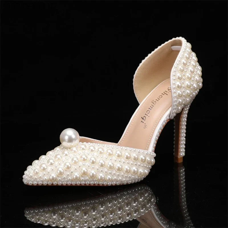 Elegant high-heeled shoe with pearls adorning the entire surface, featuring an open side design and a large pearl on the toe.