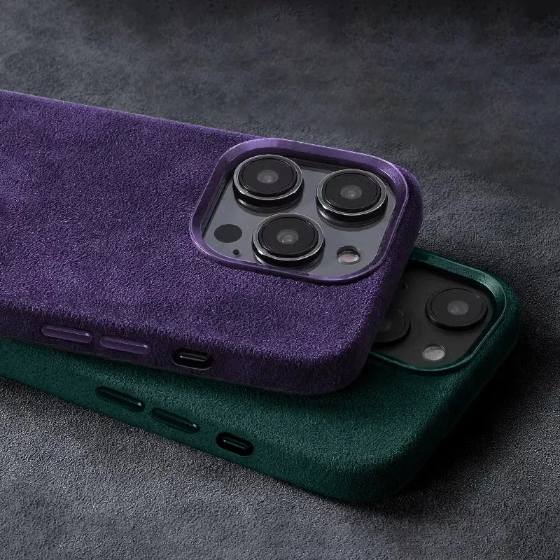 Two smartphones with textured, suede-like cases in purple and green, featuring dual cameras. The devices are stacked on a dark, textured surface.