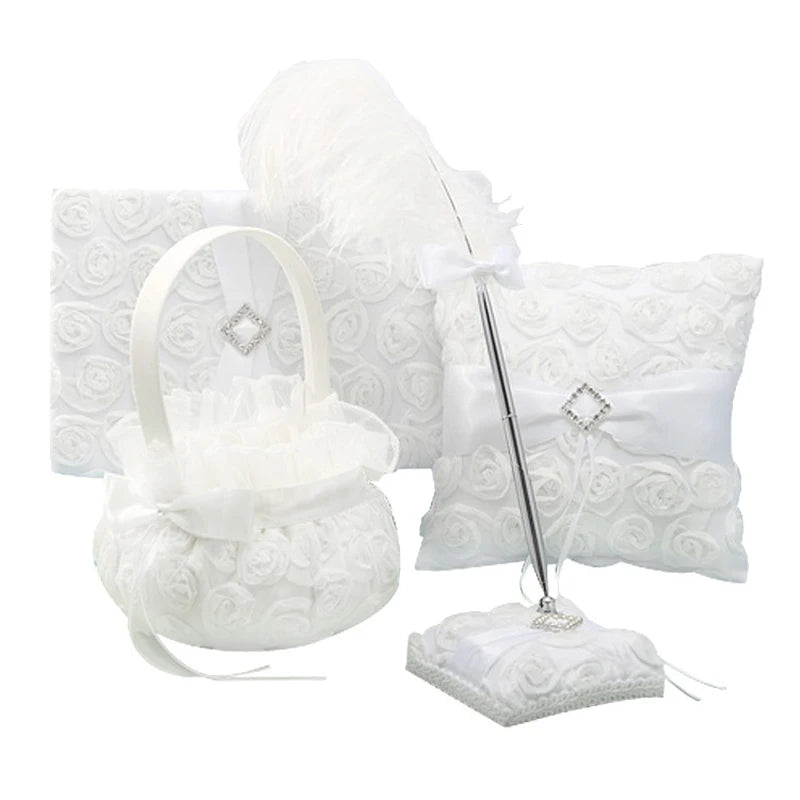 Elegant white floral-patterned wedding set featuring a ring pillow, guestbook, flower basket, and pen with feather accent, all adorned with rhinestone decorations.