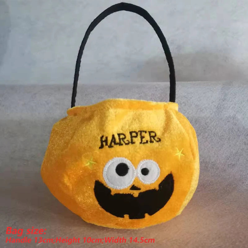 Yellow pumpkin-shaped bag with "HARPER" embroidered on top, featuring large googly eyes and a wide, smiling mouth. Black handle; dimensions provided in red text at the bottom.