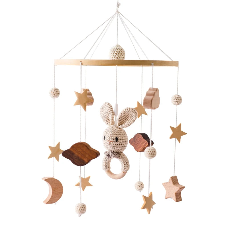 A baby mobile featuring a crocheted rabbit with various hanging elements: wooden stars, clouds, a crescent moon, and crocheted balls, all suspended from a wooden frame.